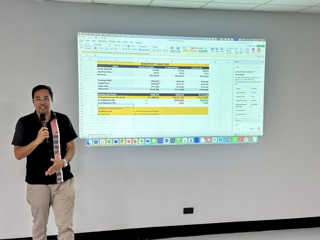 Jerry Ilao presenting a live sensitivity analysis built in Excel with AI — baseline versus absorb-cost and pass-it-on scenarios