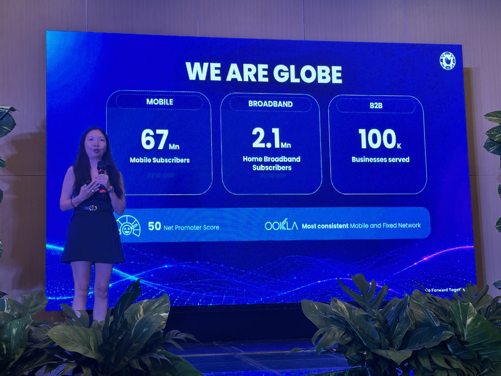 Jennifer Echevarria on stage beside a "We Are Globe" slide showing 67 million mobile subscribers, 2.1 million home broadband subscribers, and 100,000 businesses served.